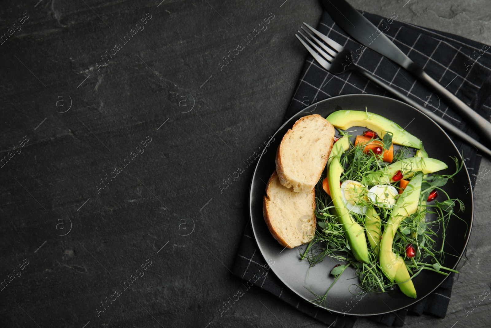 Photo of Salad with fresh organic microgreen in plate on black table, top view. Space for text