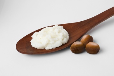 Shea butter in wooden spoon and nuts isolated on white