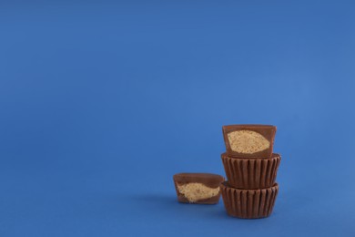 Photo of Sweet peanut butter cups on blue background. Space for text