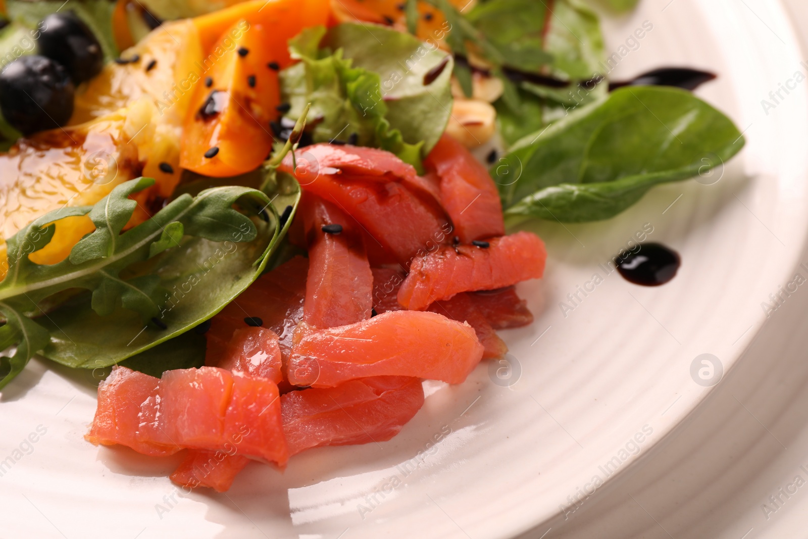 Photo of Delicious salad with salmon on white plate, closeup