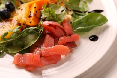 Photo of Delicious salad with salmon on white plate, closeup