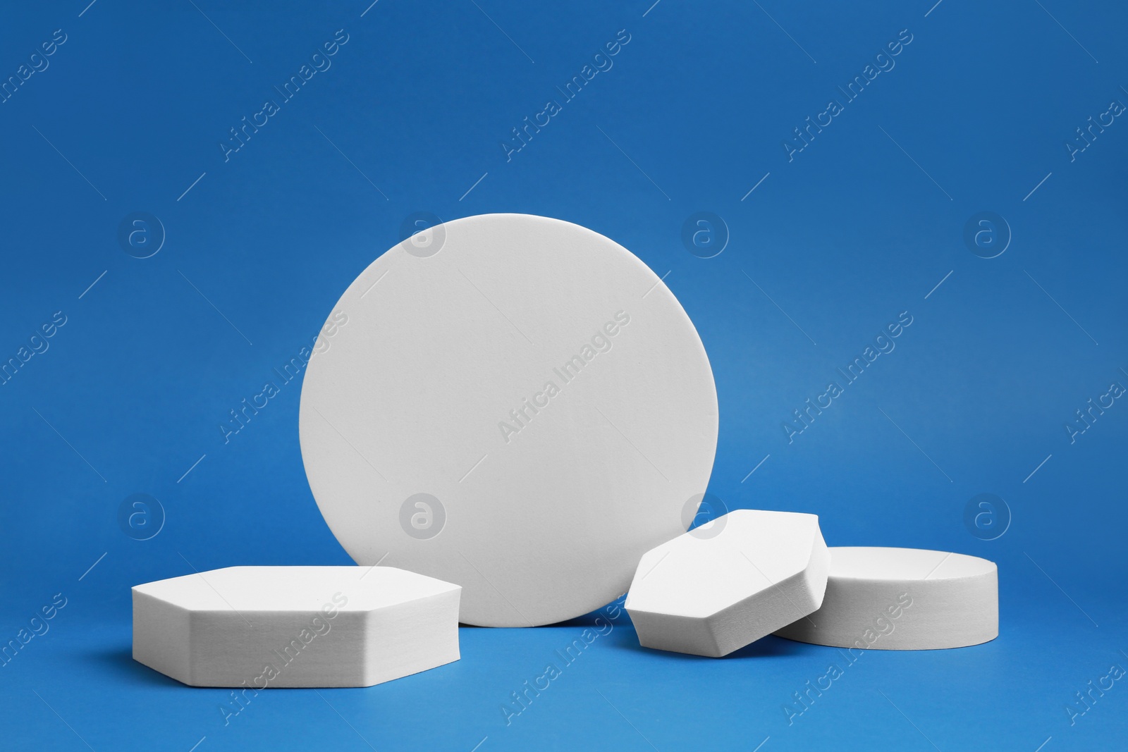 Photo of Product photography props. Podiums of different geometric shapes on blue background