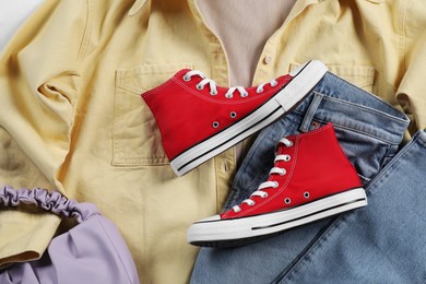 Pair of stylish red sneakers, clothes and bag, flat lay