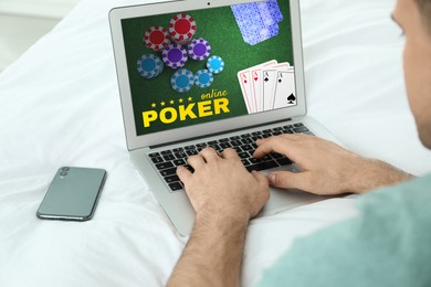 Image of Man playing poker on laptop indoors, closeup. Casino online