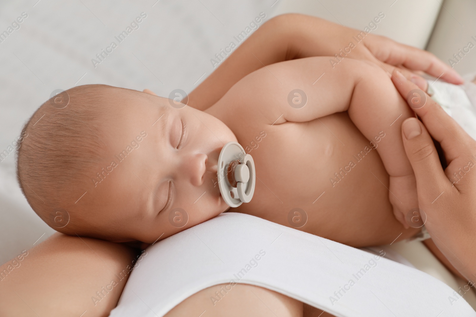 Photo of Mother holding her cute sleeping baby with pacifier at home, top view