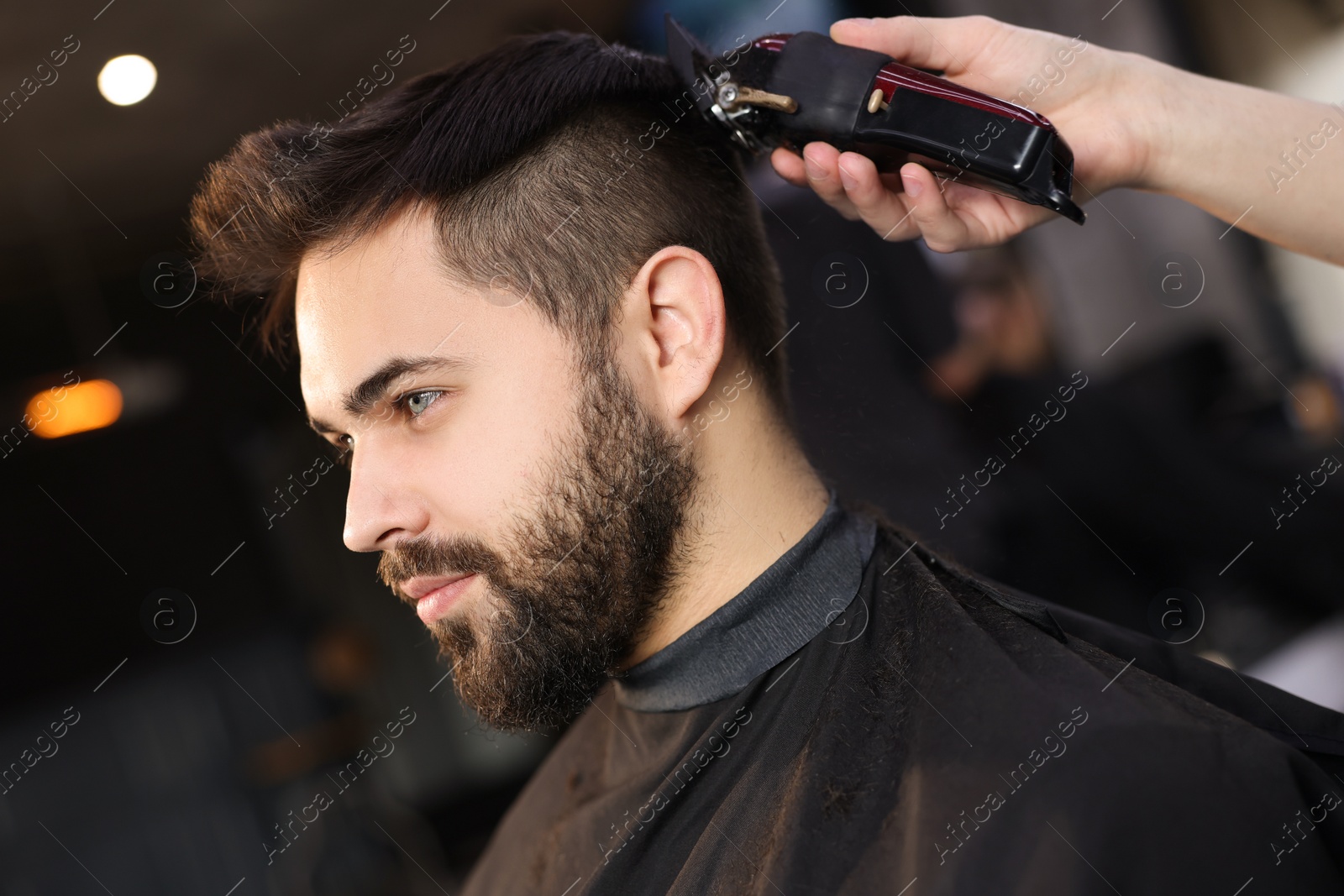 Photo of Professional hairdresser working with client in barbershop