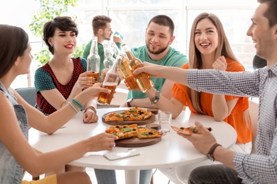 Young people having fun party with delicious pizza indoors