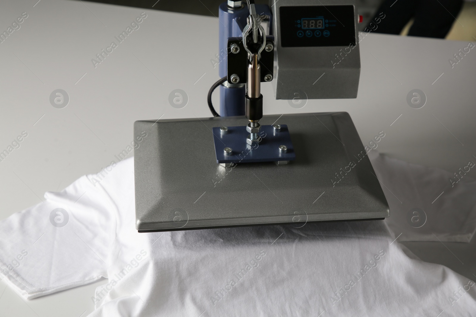 Photo of Printing logo. Heat press with t-shirt on white table