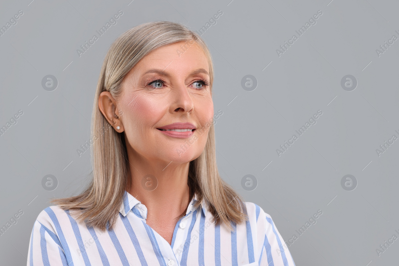Photo of Portrait of beautiful middle aged woman on light grey background, space for text