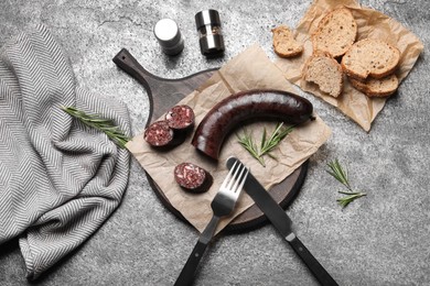 Photo of Tasty blood sausage with rosemary on grey table, flat lay