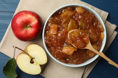 Tasty apple jam in bowl and fresh fruits on blue table, flat lay