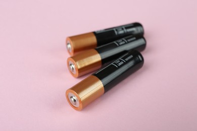 Image of New AA batteries on pink background, closeup