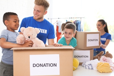 Volunteers with children sorting donation goods indoors