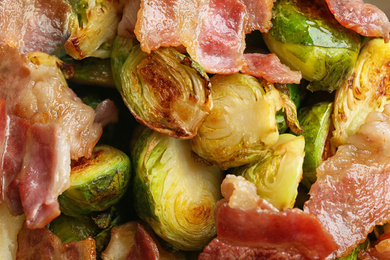 Photo of Delicious roasted Brussels sprouts with bacon in bowl, top view