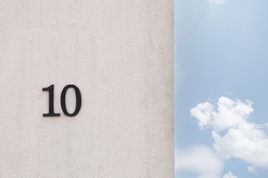 Photo of House number 10 on light textured wall outdoors. Space for text