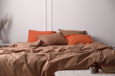 Photo of Bed with orange and brown linens in stylish room