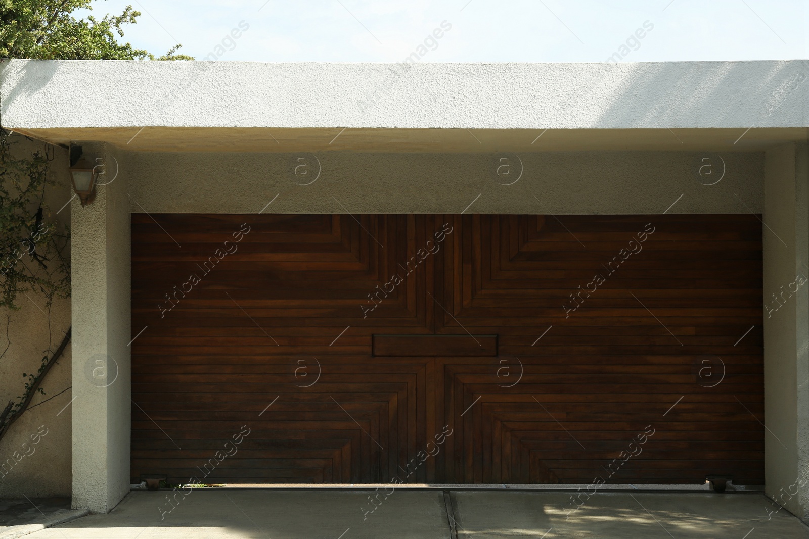 Photo of Beautiful new automated wooden gates and white wall outdoors