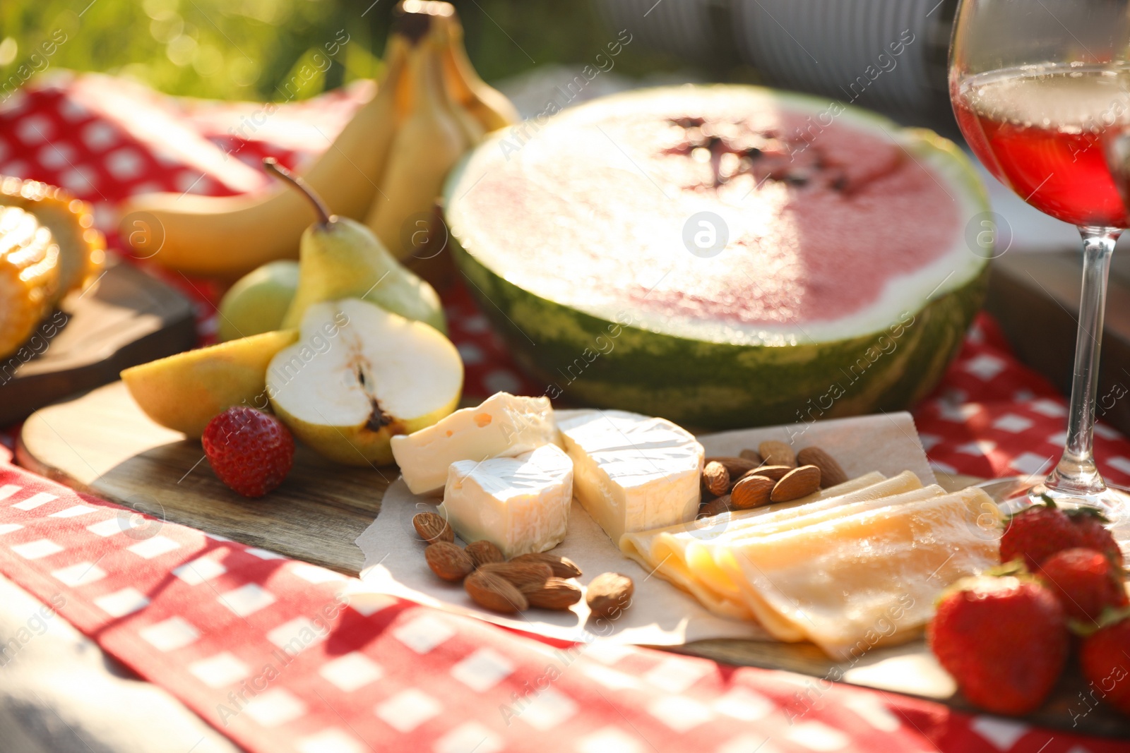 Photo of Picnic blanket with delicious food and drinks outdoors on sunny day, closeup