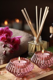 Beautiful spa composition with burning candles and different care products on wooden table, closeup