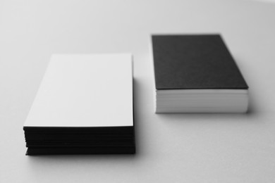 Photo of Blank black and white business cards on light background, closeup. Mockup for design