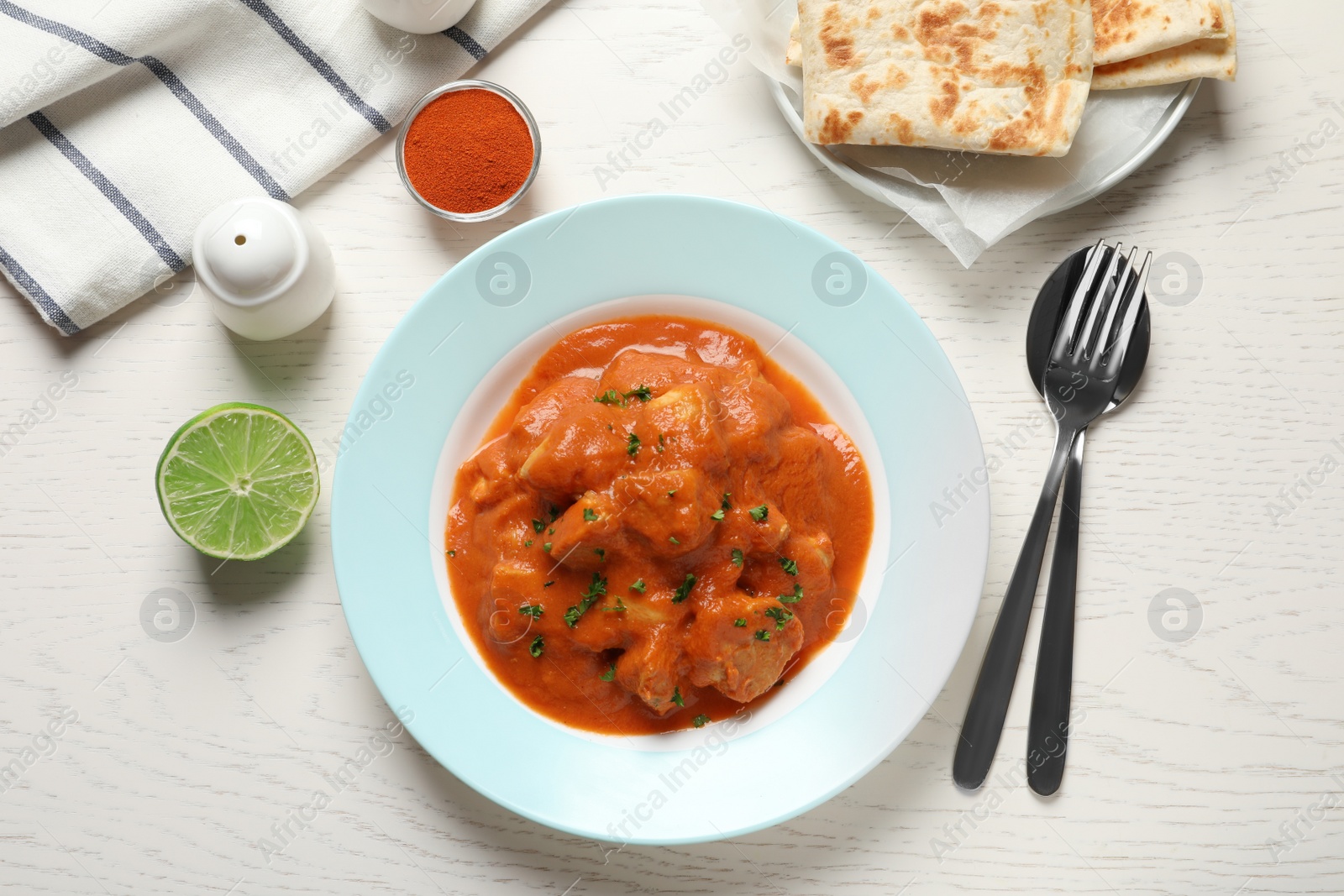 Photo of Delicious butter chicken served on wooden table, top view. Traditional Murgh Makhani dish