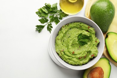 Delicious guacamole and ingredients on white marble table, flat lay. Space for text