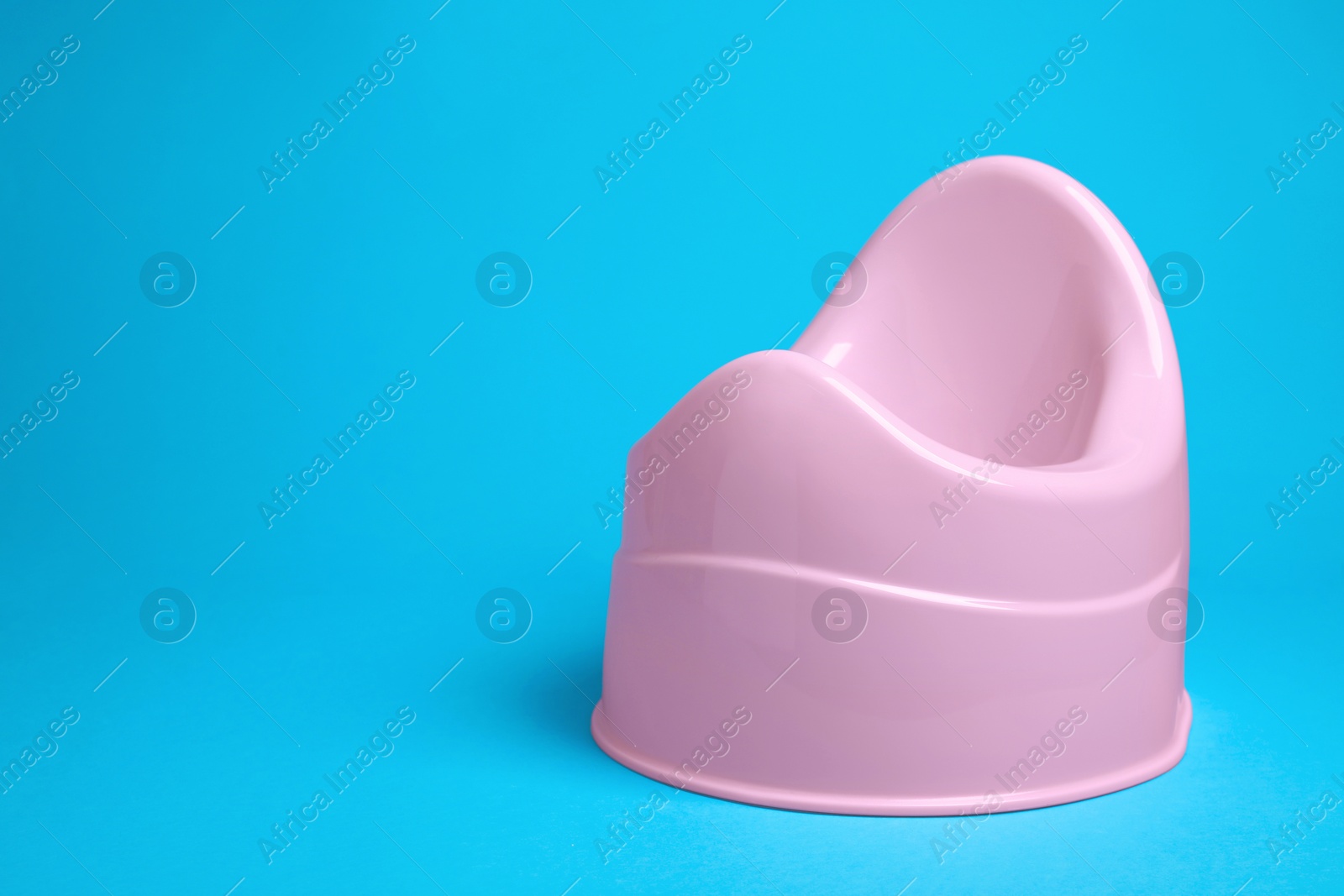 Photo of Pink baby potty on light blue background, space for text. Toilet training