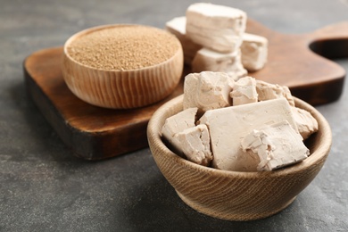 Compressed and granulated yeast on grey table