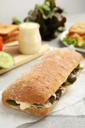 Photo of Delicious sandwich with vegetables, ham and mayonnaise on grey table, closeup