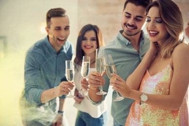 Friends clinking glasses with champagne at party indoors