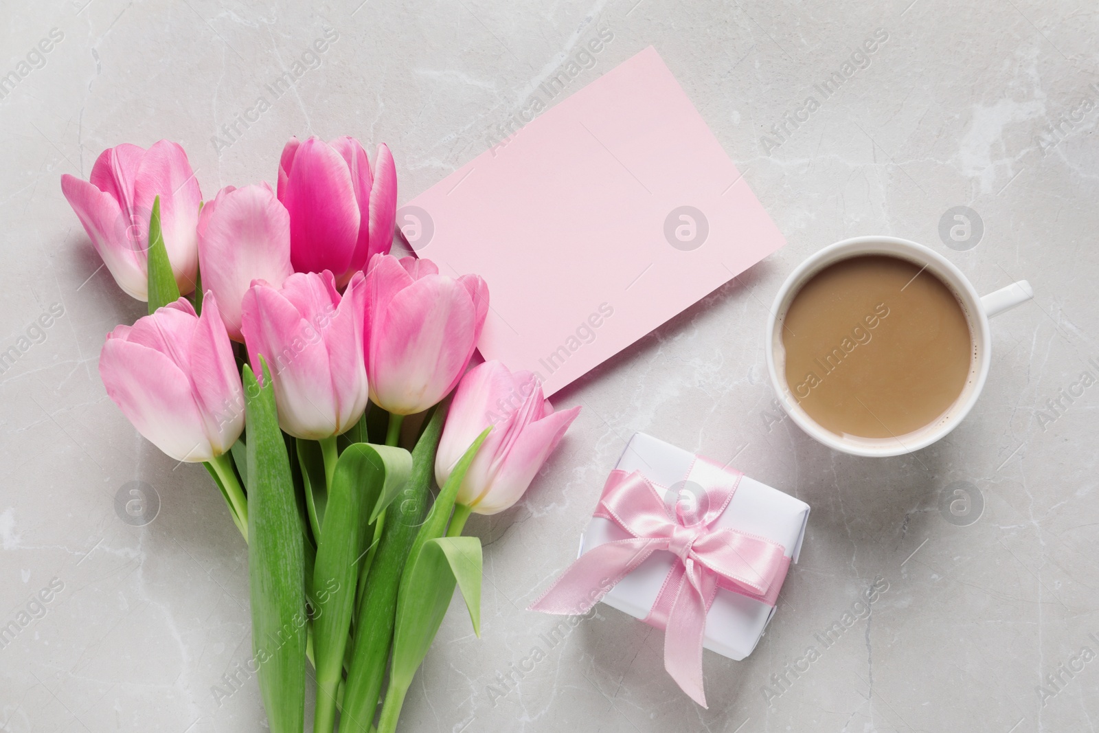 Photo of Flat lay composition of tulips and blank card on marble background, space for text. International Women's Day