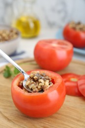 Preparing stuffed tomato with minced beef, bulgur and mushrooms on wooden board, closeup