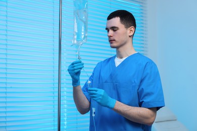 Photo of Nurse setting up IV drip in hospital, space for text