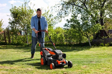 Photo of Man cutting green grass with lawn mower in garden