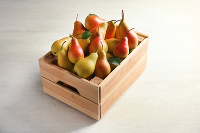 Photo of Wooden crate with ripe pears on light background