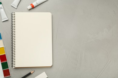 Photo of Flat lay composition with blank sketchbook on light grey stone table. Space for text