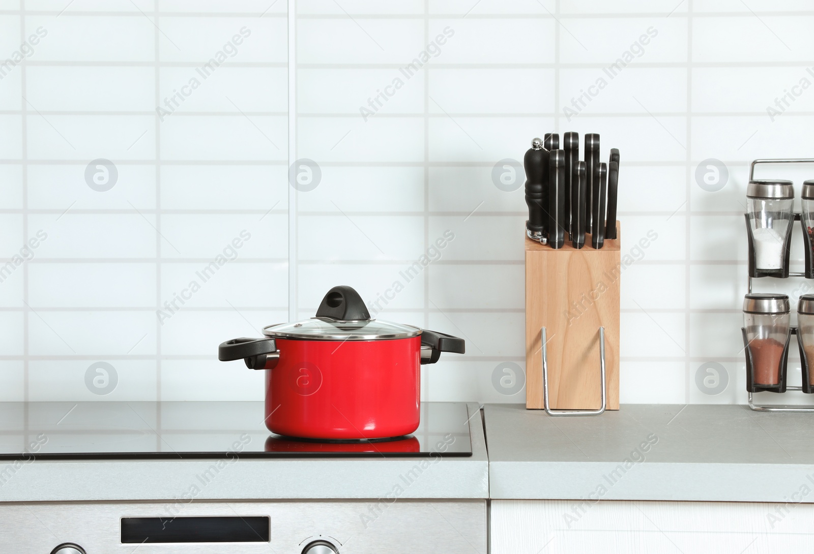 Photo of Clean pan and holder with knives in modern kitchen