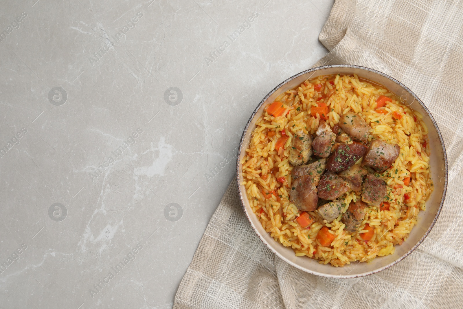 Photo of Delicious pilaf with meat on light grey marble table, top view. Space for text