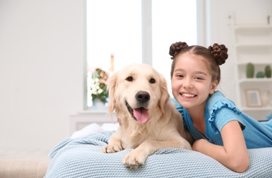 Photo of Cute little child with her pet on bed at home