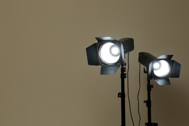 Modern spotlights against beige background, space for text