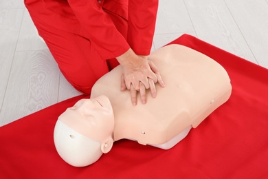 Photo of Woman practicing first aid on mannequin  indoors, closeup