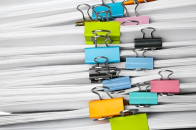 Photo of Stack of documents with binder clips as background, closeup view