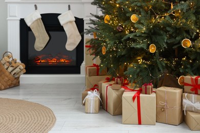 Photo of Many different gift boxes under Christmas tree and festive decor in living room