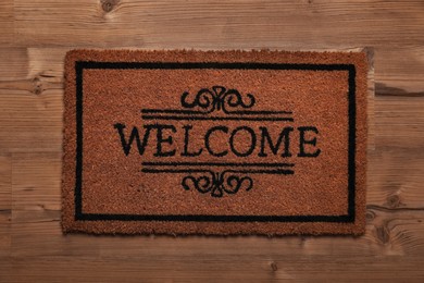 Photo of Doormat with word Welcome on wooden floor, top view