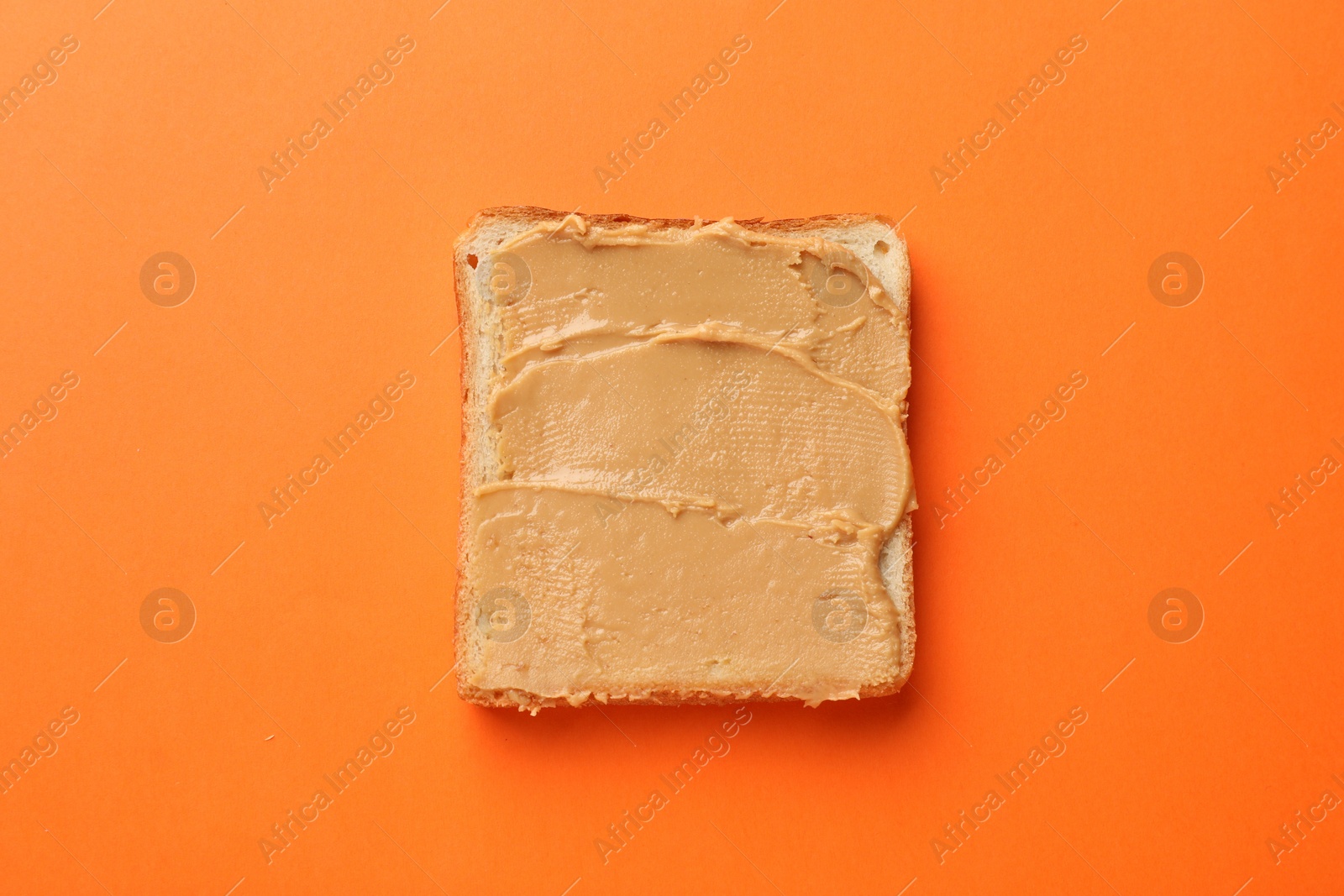 Photo of Tasty peanut butter sandwich on orange background, top view