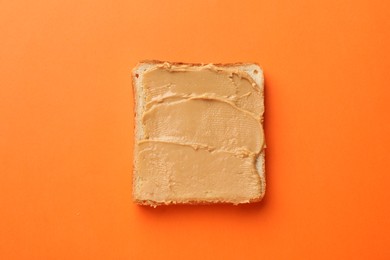 Photo of Tasty peanut butter sandwich on orange background, top view