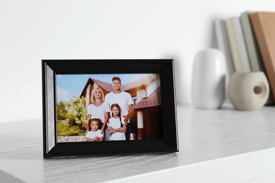Photo of Frame with family photo on white chest of drawers indoors