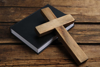 Photo of Christian cross and Bible on wooden background, closeup. Religion concept