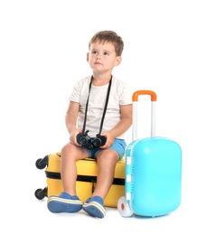 Photo of Cute little boy with binocular and suitcases on white background