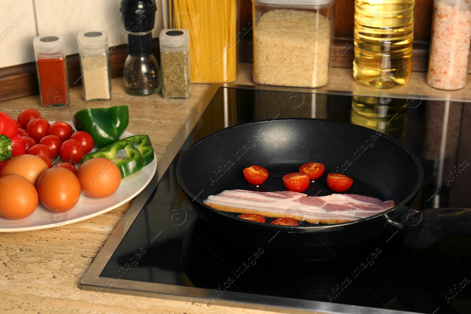 Photo of Cooking bacon with tomatoes in frying pan. Ingredients for breakfast